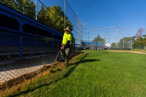crew trimming grass at baseball field 